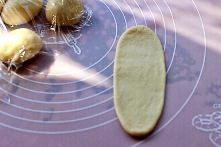 椰蓉花环面包,取一块小面团,用擀面杖擀长舌状。