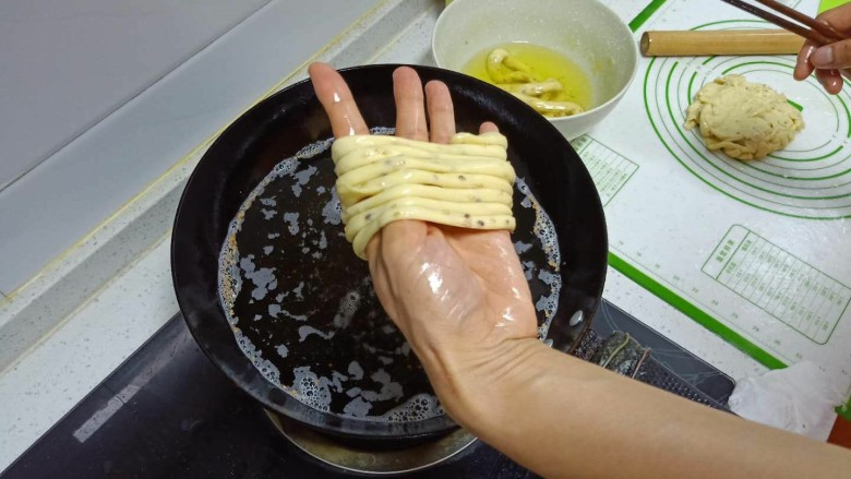 撒子,取一个醒发好的长条,缠在左手上,一边缠一边拉。