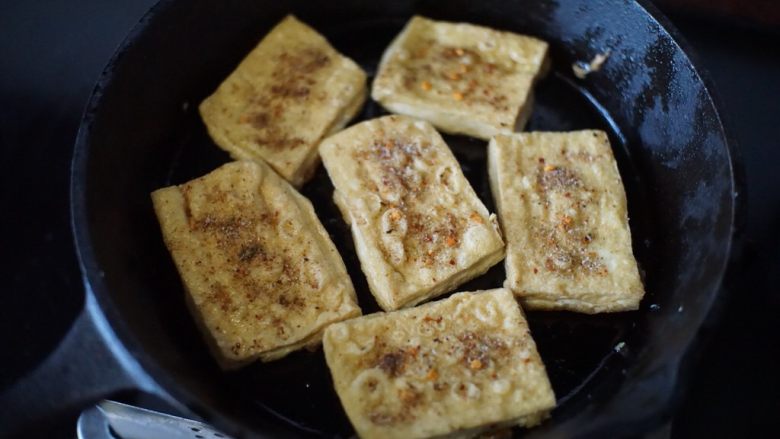铁板豆腐,然后撒入调配好的调味料,均匀撒在每块豆腐上