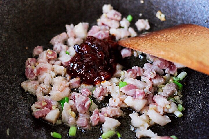 茄丁酱肉发面包,翻炒至猪肉变色时,加入黄豆酱进行小火翻炒。