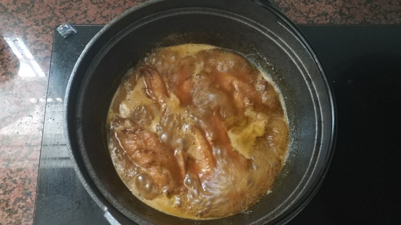 黄梅酱橙汁鸡翅,在中小火煮的过程,中途拿起盖子,把鸡中翅翻面,这样两面都会入味