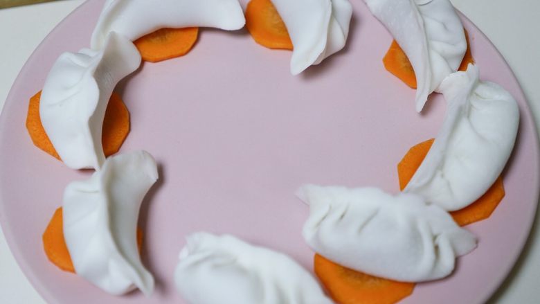 孩子超喜欢的水晶虾饺,擀成圆形饺子皮,就和普通包饺子一样步骤(这里忙着包,所以没有拍)。
馅不要太大,因为虾肉热胀冷缩,蒸的过程中还会变大一些,容易撑破饺子皮。
每个饺子下面放个胡萝卜片,可以防粘盘。