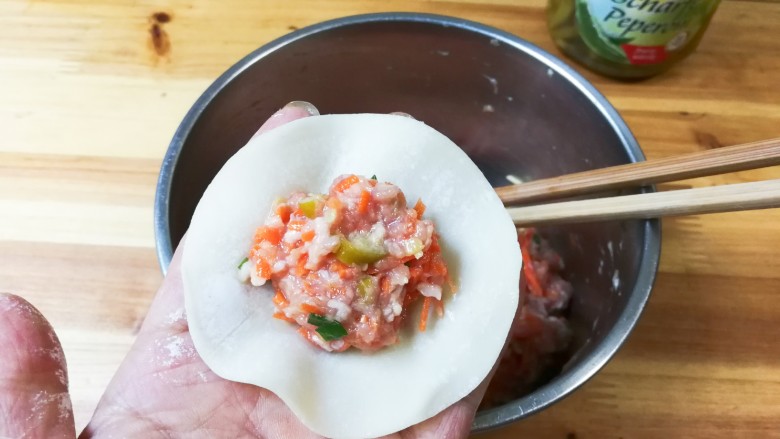 腌绿辣椒胡萝卜水饺,取一张饺皮放入肉馅