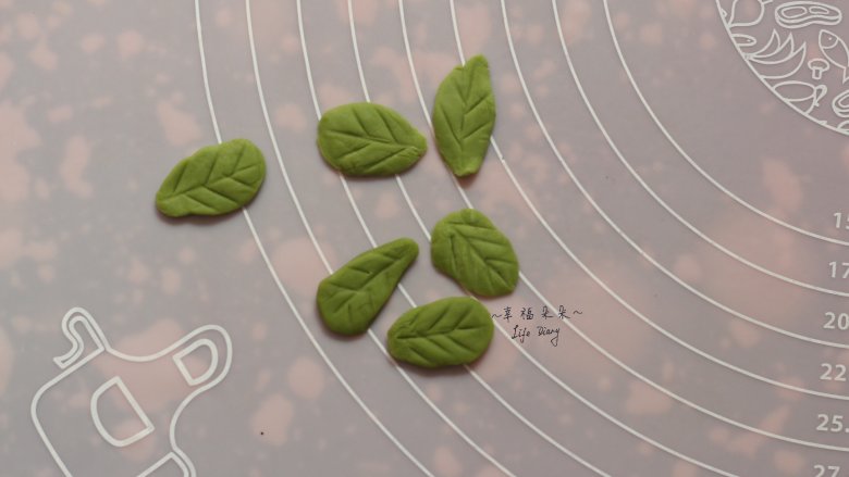 可爱的龙猫面包,然后将抹茶欧克皮面团分成6小份,整理成水滴状后压扁,再用刮板压出树叶的纹路