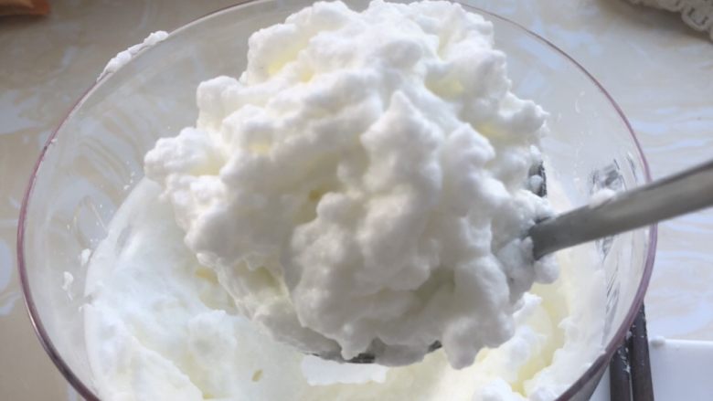 雪衣豆沙,有勺子盛上蛋清,将豆沙馅放入。