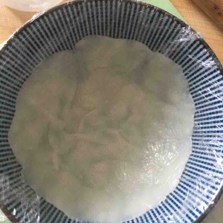 超萌熊猫雪媚娘,用一个较深的碗,铺一层保鲜膜,取一块小面团在碗内压开。