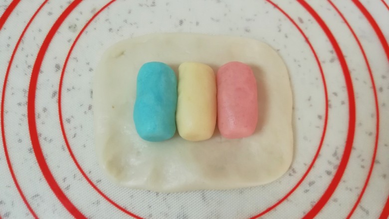 紫薯五仁酥,取一份油皮面团,按压成长方形,并排放入圆柱形油酥,一种颜色放一个(顺序无所谓)。