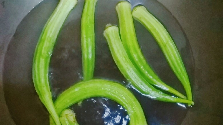 秋葵炒蛋,秋葵洗干净,放入沸水中焯变翠绿色断生捞出