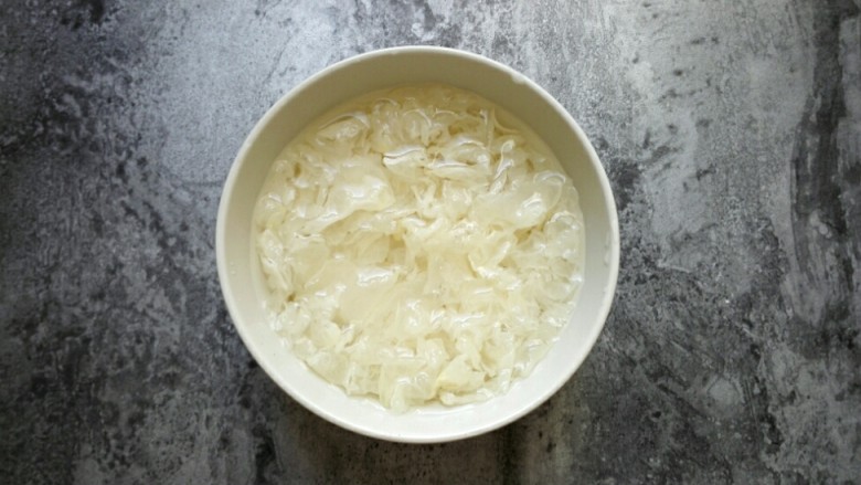 桃胶皂角米银耳羹,<a style='color:red;display:inline-block;' href='/shicai/ 232'>银耳</a>浸泡在清水里,变软后去根撕成小朵。多次搓揉换水,洗去表面杂质后,浸泡约2小时即可。