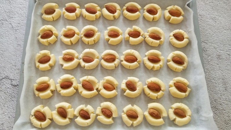 杏仁马格丽特饼干,取一个<a style='color:red;display:inline-block;' href='/shicai/ 675'>杏仁</a>放在面团上,用大拇指轻轻按压,不要太用力,避免中间太薄,随着拇指的按压会出现自然的断裂