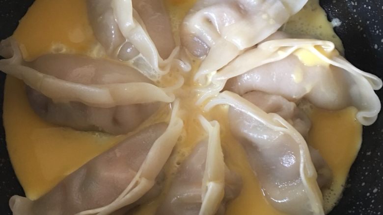 煎饺抱蛋,4️⃣ 煮至水快干时均匀倒入打散的鸡蛋液,小火煎2分钟左右至蛋液凝固。