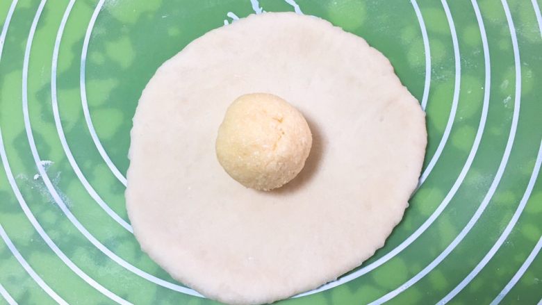 椰蓉心形面包,椰蓉馅儿分成四个剂子,滚圆。将面团剂子擀成圆饼,椰蓉馅儿放中间。