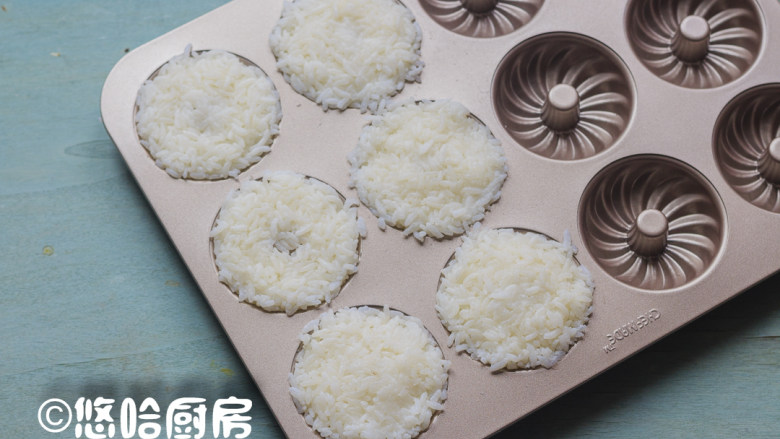 米饭甜甜圈,戴一次性手套将米饭放入甜甜圈蛋糕模具中,压紧压实,因为要给小朋友吃,米饭里没有放寿司醋。