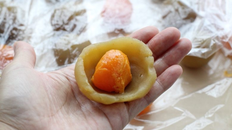 蛋黄莲蓉月饼,取一个莲蓉馅放在手心压扁,然后放上蛋黄