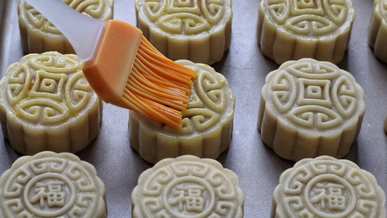 蛋黄莲蓉月饼,取出在表面薄薄的刷一层蛋黄液,再放回烤箱继续烤15-18分钟