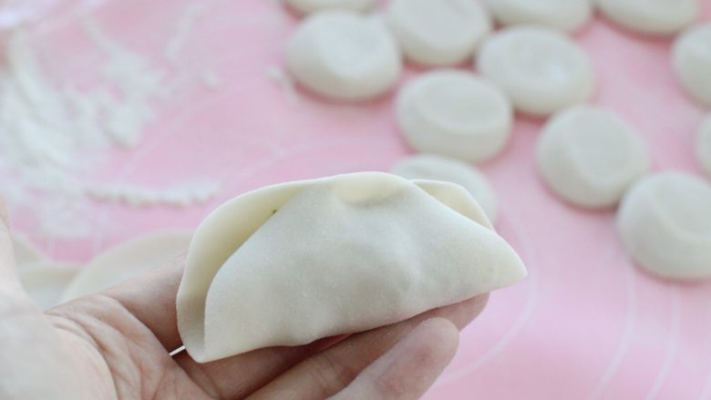 猪肉芹菜煎饺,取一个饺子皮放上适量馅料,将饺子皮中间部分对折捏严