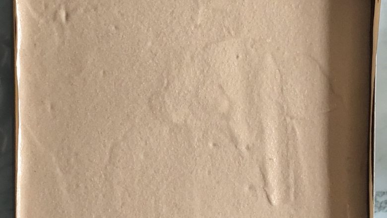 可可蛋糕卷,倒入烤盘,刮刀抹平,重重的震两下,震出气泡,