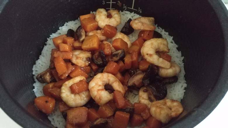 南瓜虾仁焖饭,米饭还差5分钟成熟的时候,放入炒好的虾仁南瓜,盖上盖子继续焖饭5分钟至焖饭程序结束。