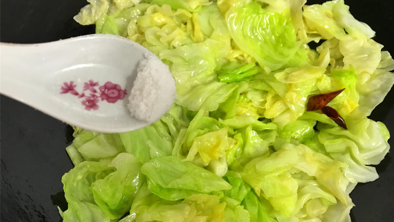 炝炒手撕包菜,快速翻炒均匀,让菜叶都沾上油汁后,加入适量的盐。