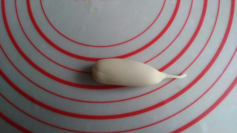 象形白萝卜馒头,将面团搓成圆柱形,再把其中一端搓出长长的主根。