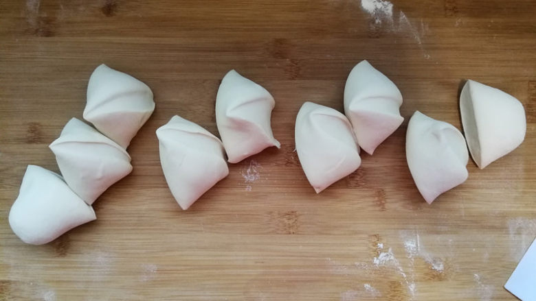 韭菜鸡蛋馅儿包子,发酵好的面团取出,案板上撒干面粉,将面团揉压排气。重新揉光滑搓长,分成8份。