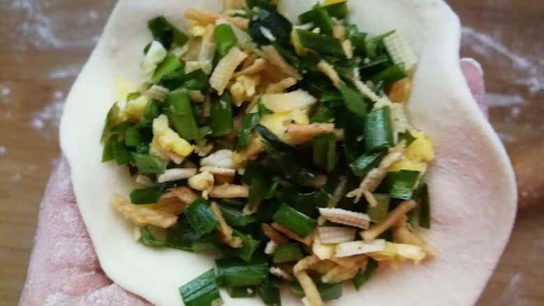 韭菜鸡蛋馅儿包子,取一块面团,擀圆,包入馅儿料。面团不要擀的太薄,要想面团宣软,外皮可以稍微厚一些。