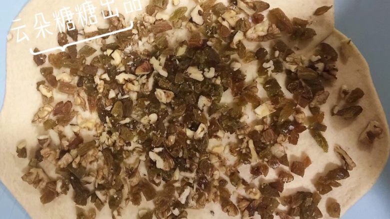 坚果面包,醒发好的面团,用擀面杖擀成长方形,把切碎的核桃仁和葡萄干均匀的铺在已经擀好的长方形面团上。
