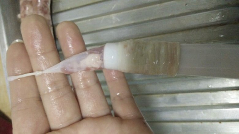 自制脆皮肠~好吃又放心,将肠衣整条的套在灌肠工具漏斗处,这一步可以先将肉馅挤压一点到漏斗口的地方,借助油脂的润滑作用,很容易就可以将肠衣套进去,肠头记得打个结哦。