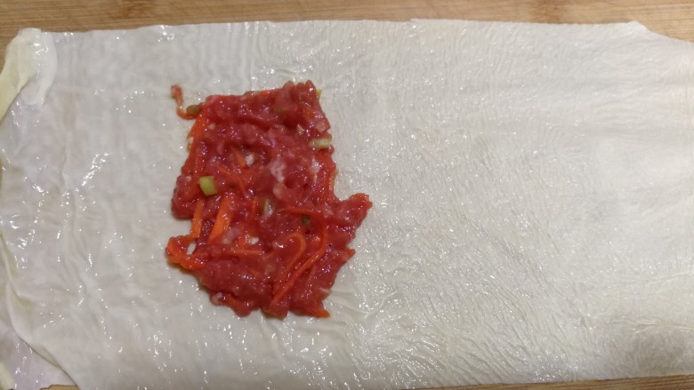 美味煎豆皮,第一张切好的豆皮儿放在案板上,抹上肉馅儿。