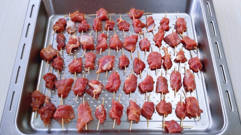 火爆朋友圈的牙签肉,一口一串!好吃到停不下来!,将串好的牙签肉依次摆放在烤盘上,我的这烤盘是有洞洞眼的!如果不是这种烤盘直接将牙签肉摆放放烤网上也可以!