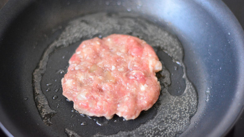 美式牛肉汉堡,平底锅放少量的食用油,烧热,然后放入肉饼,大火先把两面各煎1分钟,让表面熟透,转最小火,盖上锅盖,焖上3-5分钟,让里面的肉馅熟透