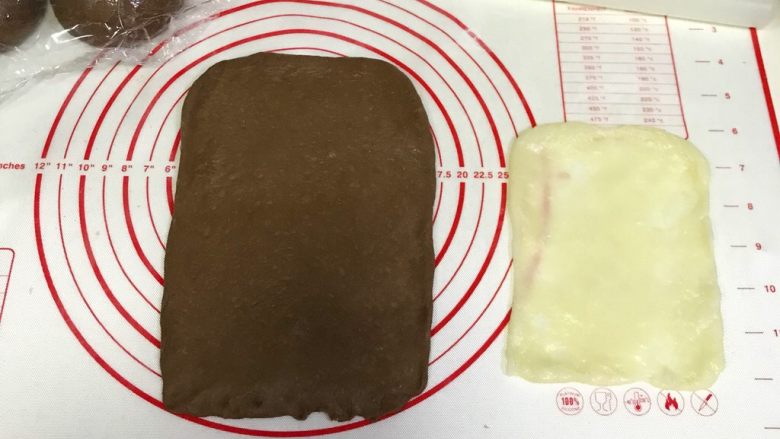 咖啡可可麻薯软欧包,取一份松弛好的面团,用手拍扁,用擀面杖把面团擀开,翻面再擀会,用手整理成长方形,压薄底边。取一份麻薯,继续用擀面杖擀成比面片小点的长方形。