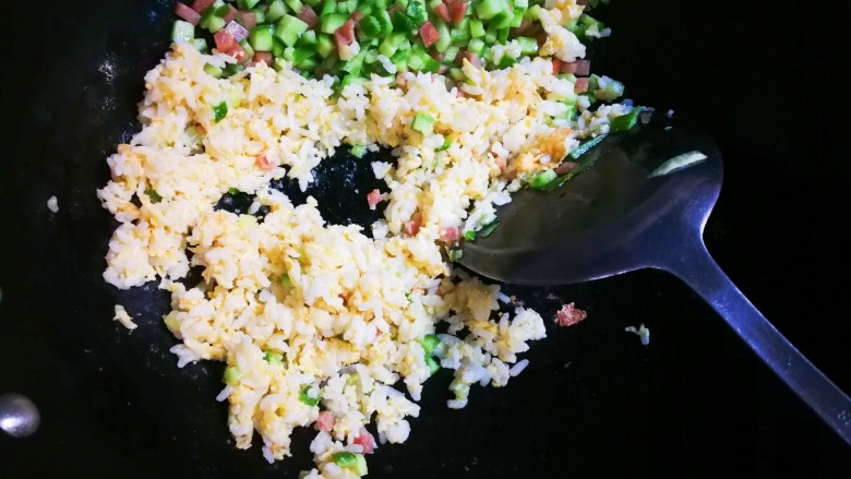 十味 午餐肉黄瓜蛋炒饭,将午餐肉黄瓜推到锅一边,放入拌上蛋液的米饭,翻炒至熟