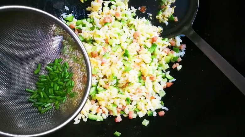 十味 午餐肉黄瓜蛋炒饭,撒入葱花翻炒均匀