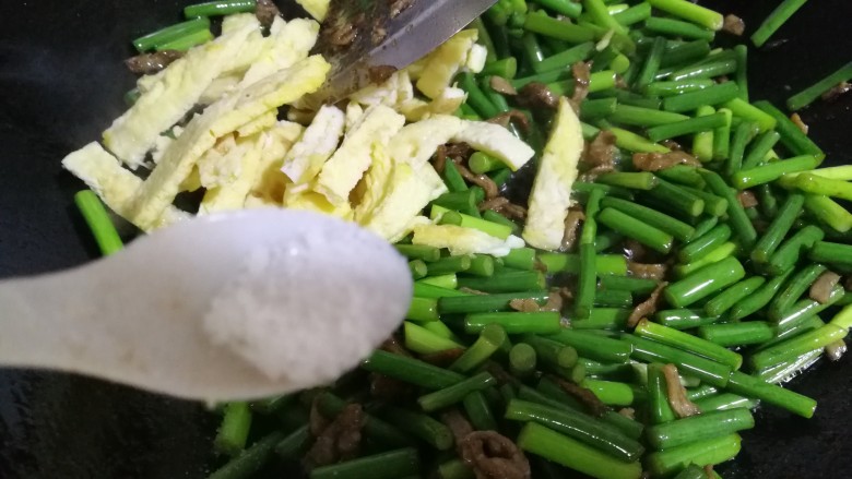 牛肉蒜薹炒蛋条,在将蛋条放入并一起放1.5勺盐,继续炒几下,出锅前倒一点水烹一下。