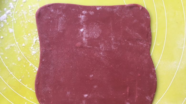双色牛角酥,将红色面团擀成方形,不用太大,之后包裹油纸装入保鲜袋入冰箱冷冻