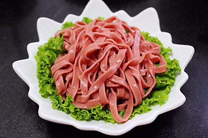 十味 美味油泼面,把过水的面条沥干水份后,盘子底下铺上一层生菜,上面放入做好的面条。