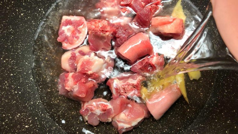 猪尾骨炖石橄榄,猪尾骨放入锅里,放入姜片,倒入和食材齐平的水,大火把水烧开。