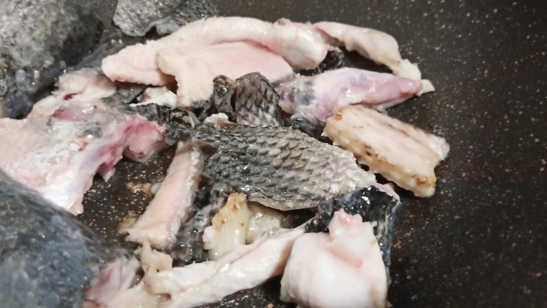 十味 记忆里的味道《酸菜鱼片面》,锅里加适量的油、放生姜片、蒜翻炒出香味、加鱼骨煎至两面微黄。