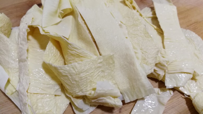 牛肉丝炒油豆皮,将整张的油豆皮儿放在案板上,切成条。