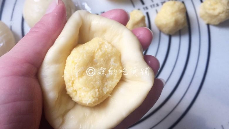 椰蓉花朵面包,取一个醒发好的面团,按扁,把椰蓉馅放入。帮好的面团收口向下,再用擀面杖或者用手把它压成扁圆形