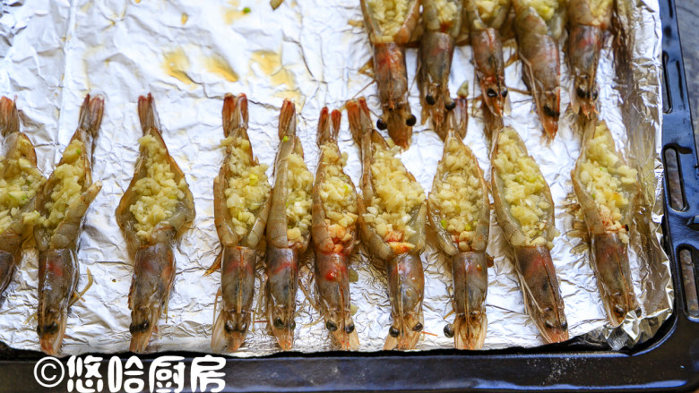 烤蒜蓉开背虾,烤盘铺锡纸,开背虾平铺在烤盘上,在开背的地方填上一勺蒜蓉,依次填满全部的虾。