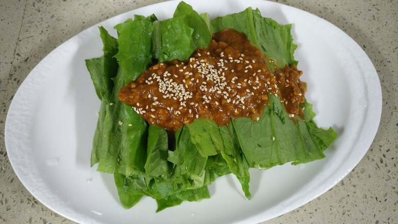 麻酱油麦菜,将调好的料汁倒入油麦菜上,撒上炒熟的白芝麻,拌匀就可以了。
