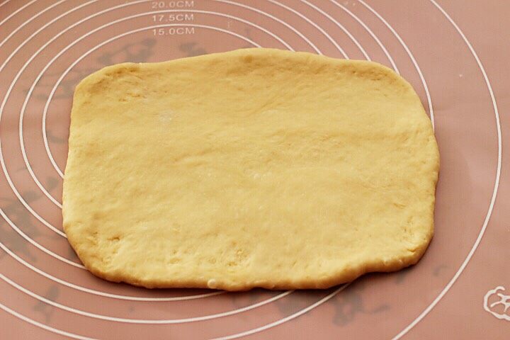 超级的软妹子牛奶豆沙吐司,取一块面团,用擀面杖擀开,将气泡拍破。