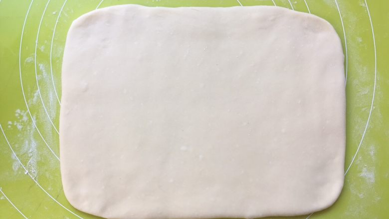 双色牛角酥,揉面垫上撒点干粉将白色面团擀成长方形,大小为小号保鲜袋的大小,之后包裹上油纸,装入保鲜袋入冰箱冷冻