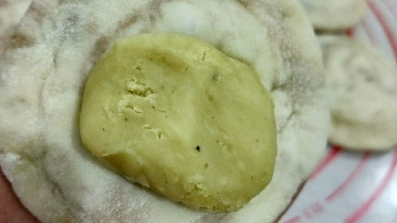 钳花绿豆包,取个剂子擀成中间厚周围薄的面皮,放入适量绿豆馅,包好并搓圆。