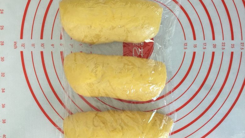 南瓜奶油吐司,卷起,盖上保鲜膜醒发15分钟。