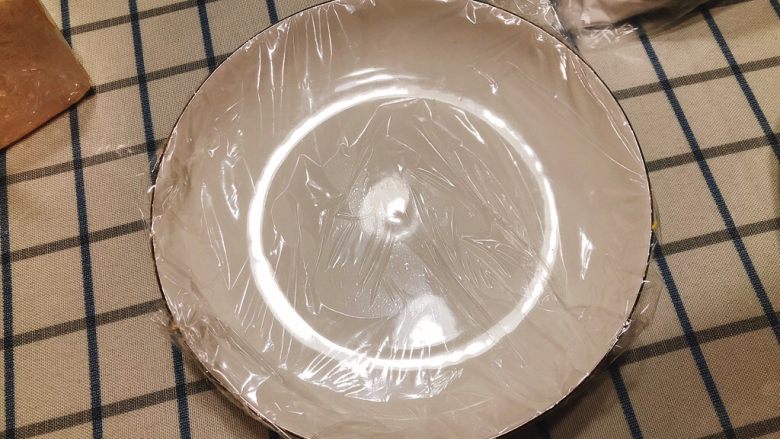 咸味南瓜饼,取一个空盘子,包上保鲜膜。(若量做的大,不是一次性吃完的话一定要在碗里包一层保鲜膜,否则冷冻后南瓜饼无法脱盘)