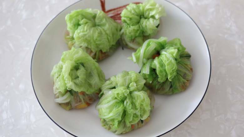 百财福袋,用韭菜将白菜包系好,放入盘中。
