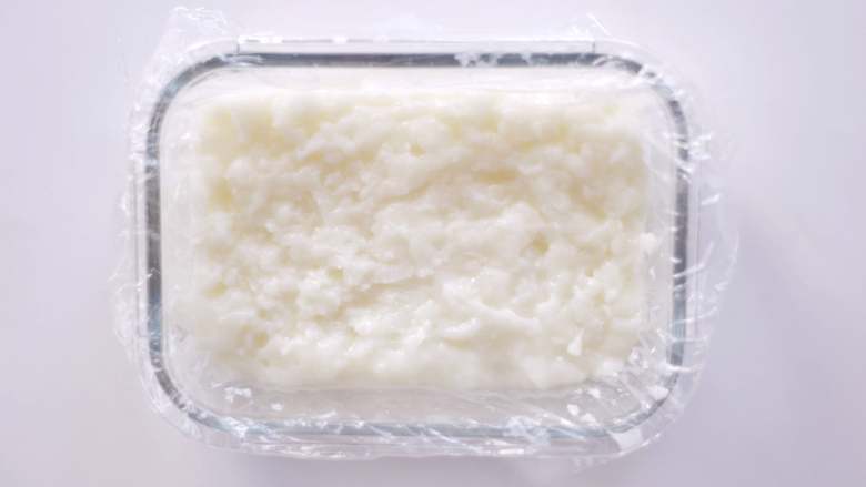承味延世牛奶的椰蓉小奶冻 ,把奶糊倒入铺好保鲜膜的保鲜盒中,上下震几下让表面更平整。